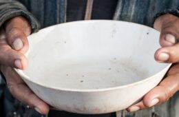 close up of a beggar holding an empty bowl