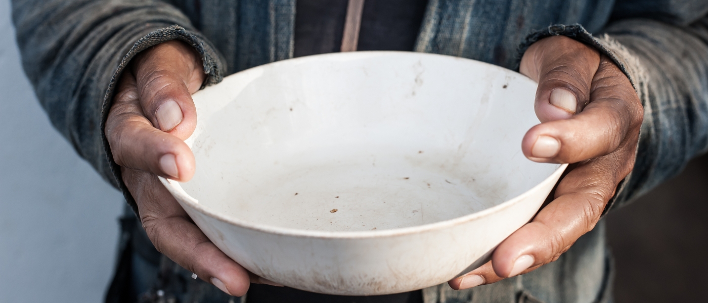 close up of a beggar holding an empty bowl