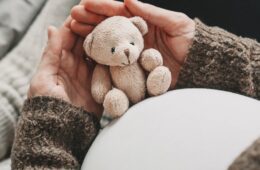 Close up of expecting mother holding a teddy bear.