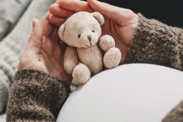 Close up of expecting mother holding a teddy bear.