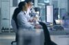 photo of two women in lab coats looking at computer screen