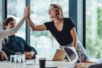 Two people high five each other while sitting in a group work setting