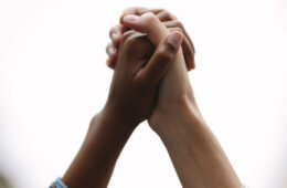 Photo of two hands clasped together up in the air