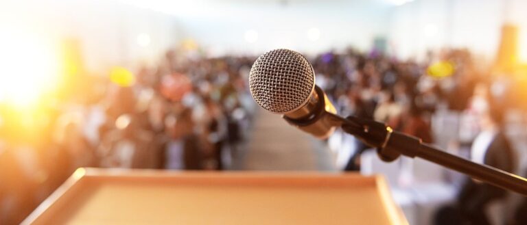 Microphone in front of podium with crowd in the background