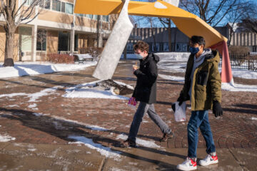 Photo of students walking in front of the Start sculpture in North Residential Village with snow surrounding them
