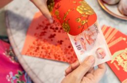 Close-up of hands preparing Chinese New Year red packets during Chinese New Year festive period Notes to Inspector/Editor. Golden text on red packet is general Chinese greeting words for prosperity.