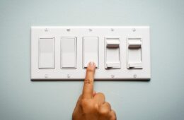Woman's hand on a light switch showing that she is turning off the power and electricity to conserve energy