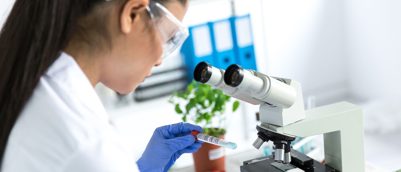 Female microbiologist using microscope in laboratory