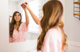 Happy woman seen from behind drawing a heart in the bathroom mirror with a lipstick during a self care day