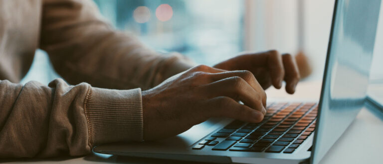 Close-up photo of hands typing on a laptop