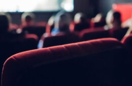Photo from behind of movie theater seating with blurred people in some of them