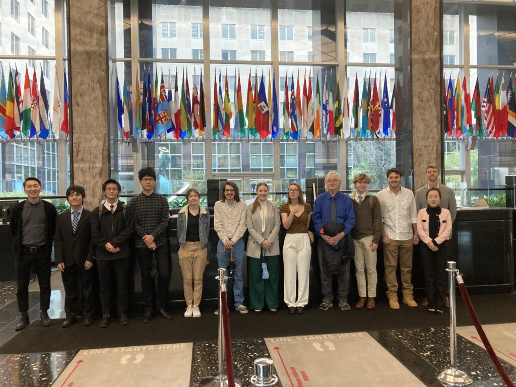 Students and faculty members pose for a photo in Washington DC in front of international flags