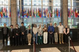 Students and faculty members pose for a photo in Washington DC in front of international flags