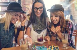 Young smiling women sitting in a cafe and having fun while playing board game.