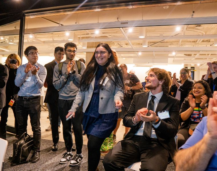 Crowd clapping as female attendee walks forward at 2023 Morgenthaler-Pavey Startup Competition, captured by Character Studies Photography.