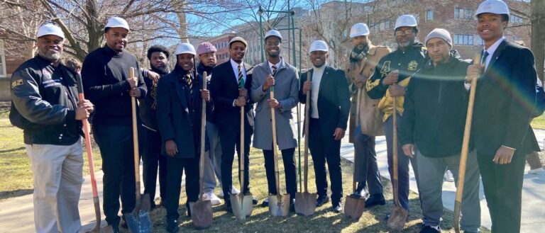 Members of Alpha Phi Alpha Fraternity, Inc. smile while wearing hard hats and holding shovels on the CWRU campus.