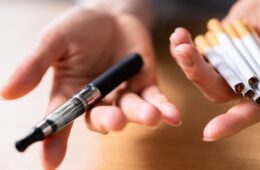 Woman's Hand Holding Vape And Tobacco Cigarettes