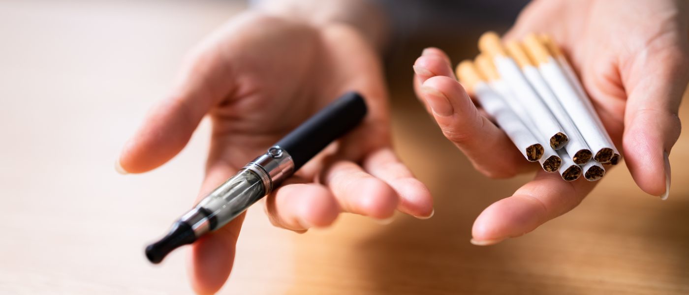 Woman's Hand Holding Vape And Tobacco Cigarettes