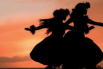 Two Hawaiian hula dancers move gracefully before the warm glow of the tropical sunset. Image provided by Getty Images