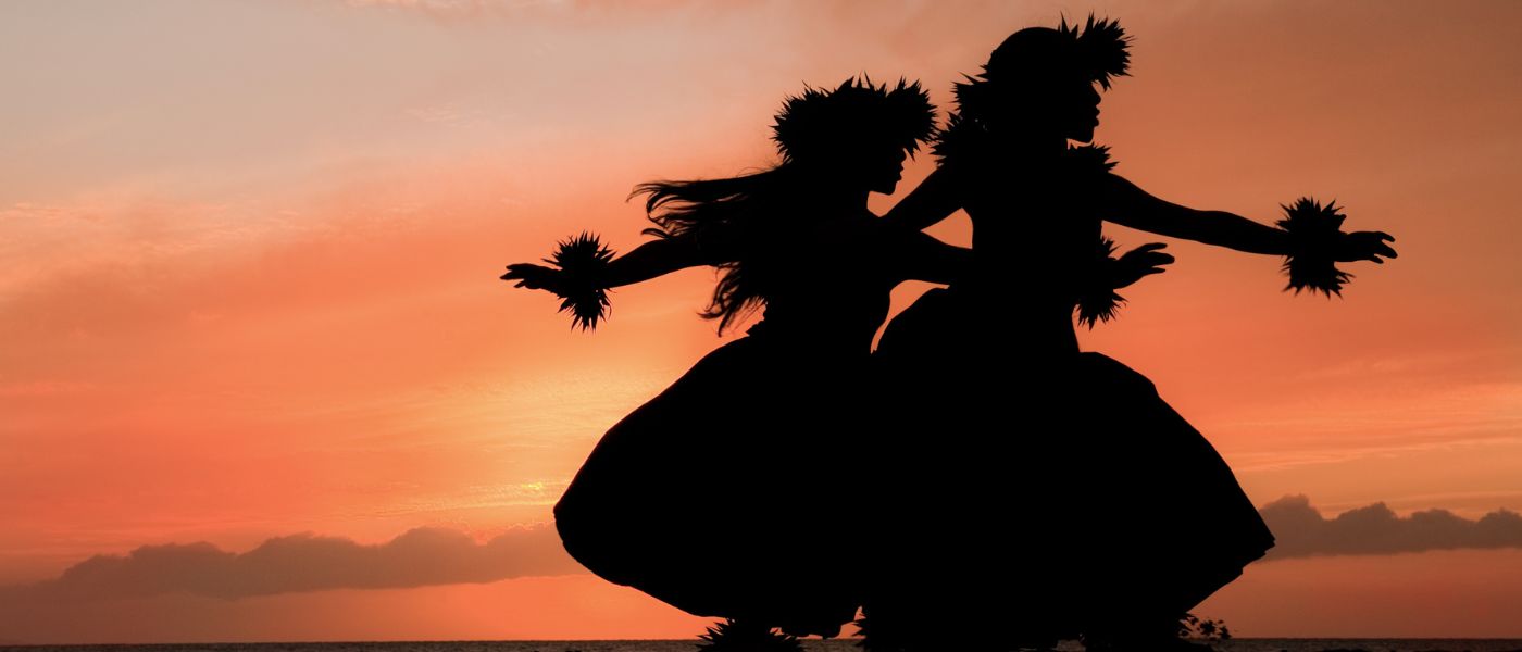 Two Hawaiian hula dancers move gracefully before the warm glow of the tropical sunset. Image provided by Getty Images