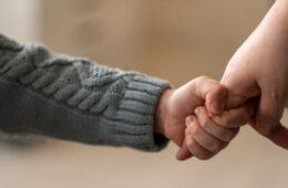 Close up photo of a young child holding the finger of an adult