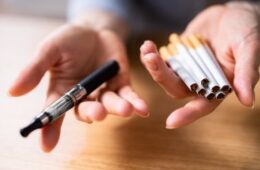 Woman's Hand Holding Vape And Tobacco Cigarettes