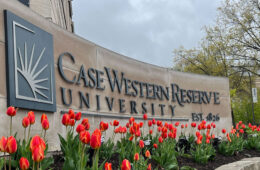 Photo of the CWRU sign on the corner of Adelbert and Euclid with tulips in front of it