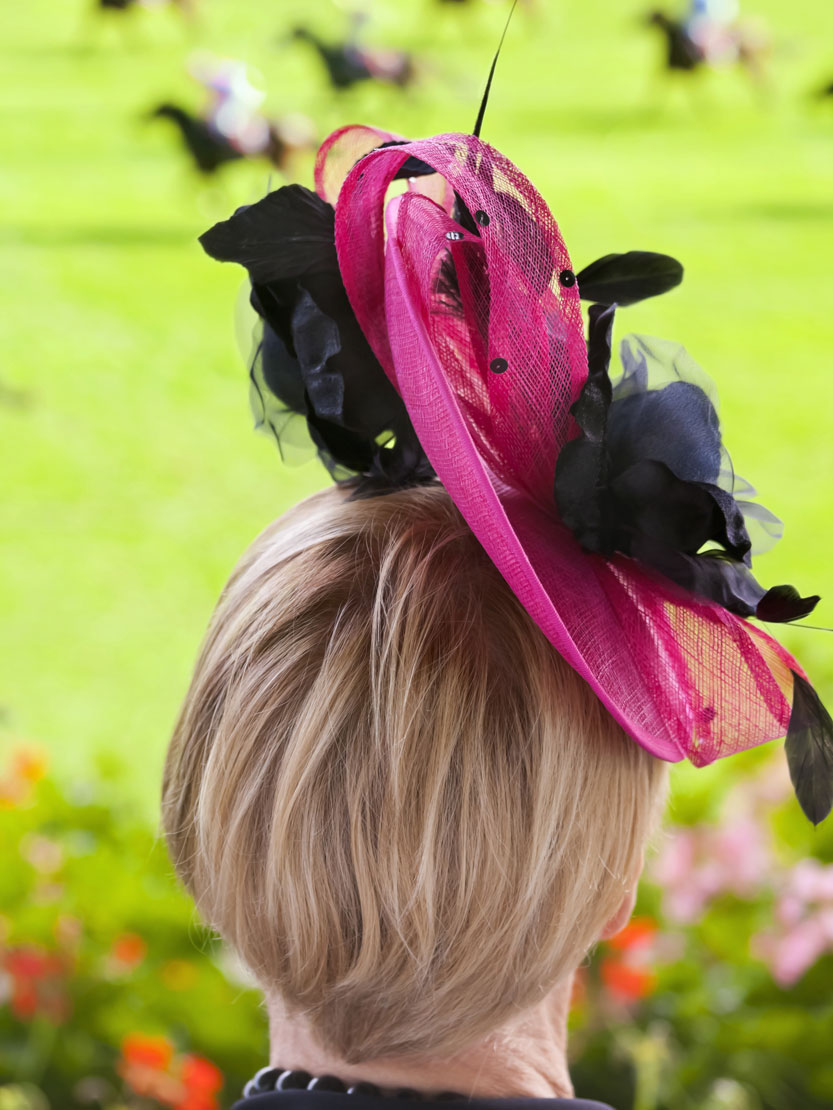 Photo from behind of a person wearing a hot pink and black hat during the Kentucky Derby