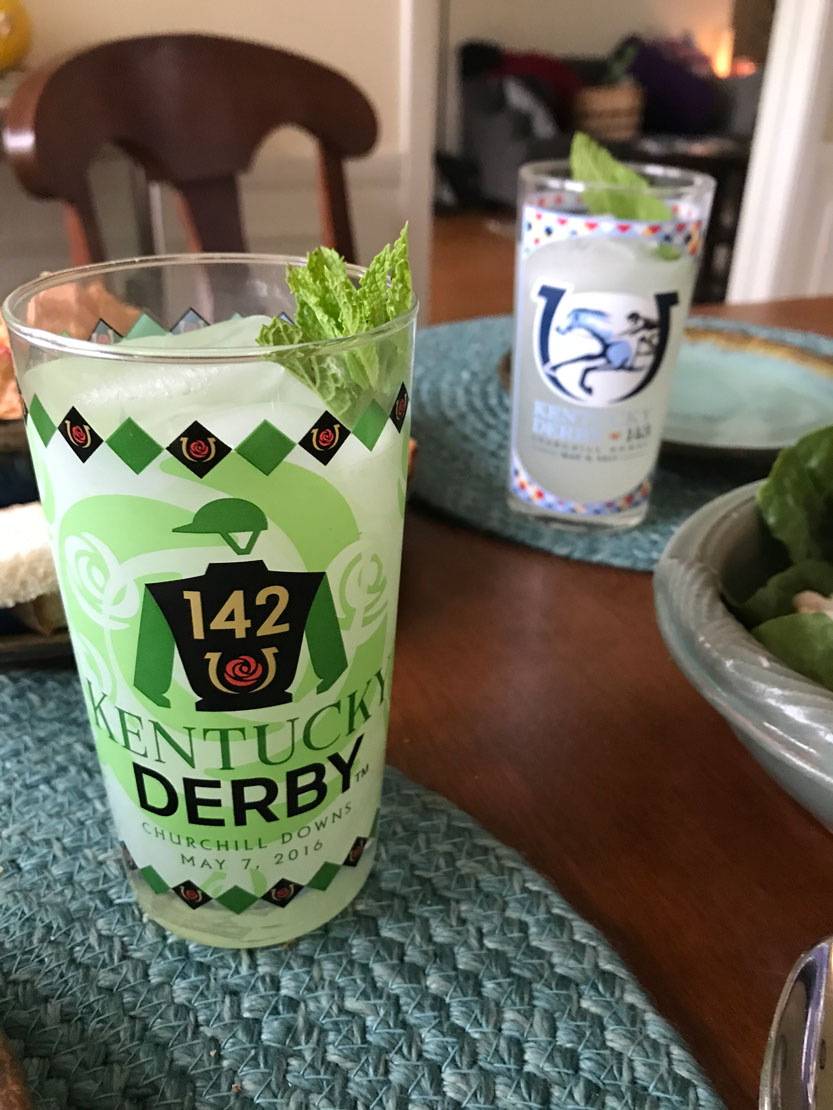 Photo of commemorative Kentucky Derby glasses filled with mint julep on a table