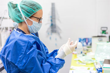Photo of a nurse researcher putting on gloves in the lab