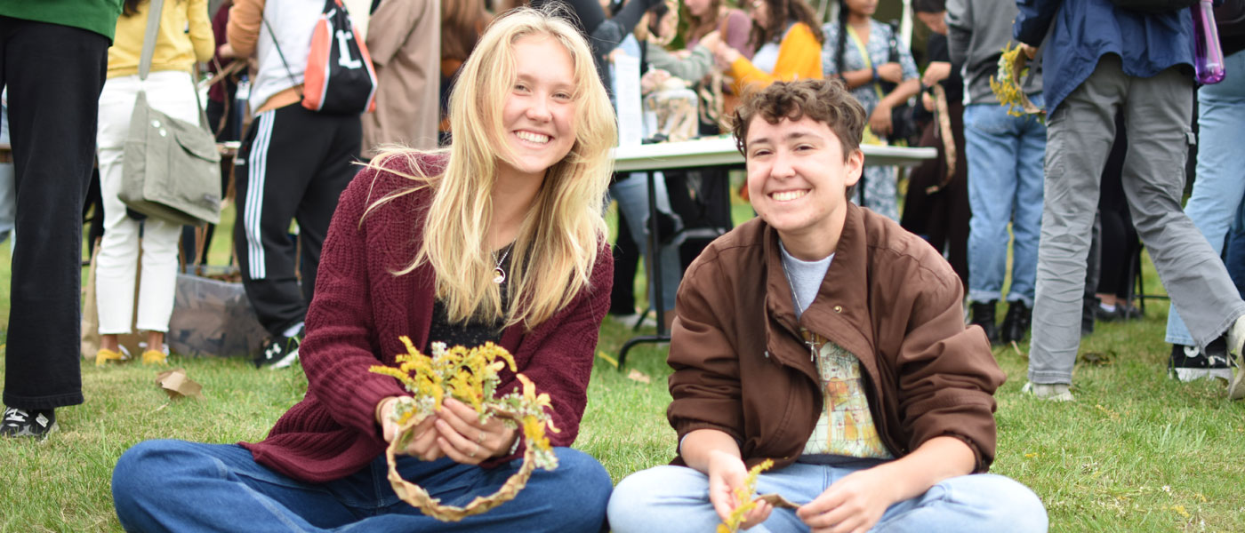 Photo of two CWRU students smiling as they make flower crowns