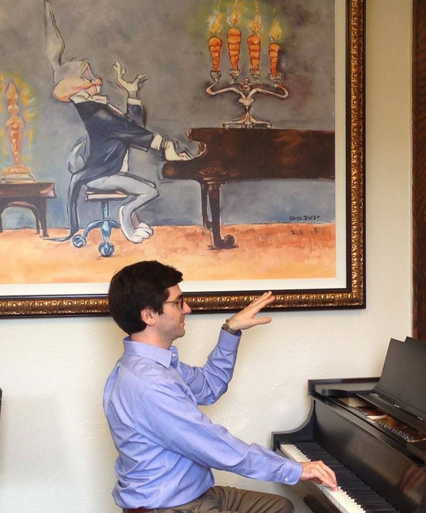 Photo of David Rothenberg playing piano and posing with his hand up like a photo of Bugs Bunny behind him
