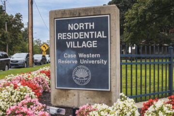 Photo of the North Residential Village sign on the CWRU campus surrounded by flowers