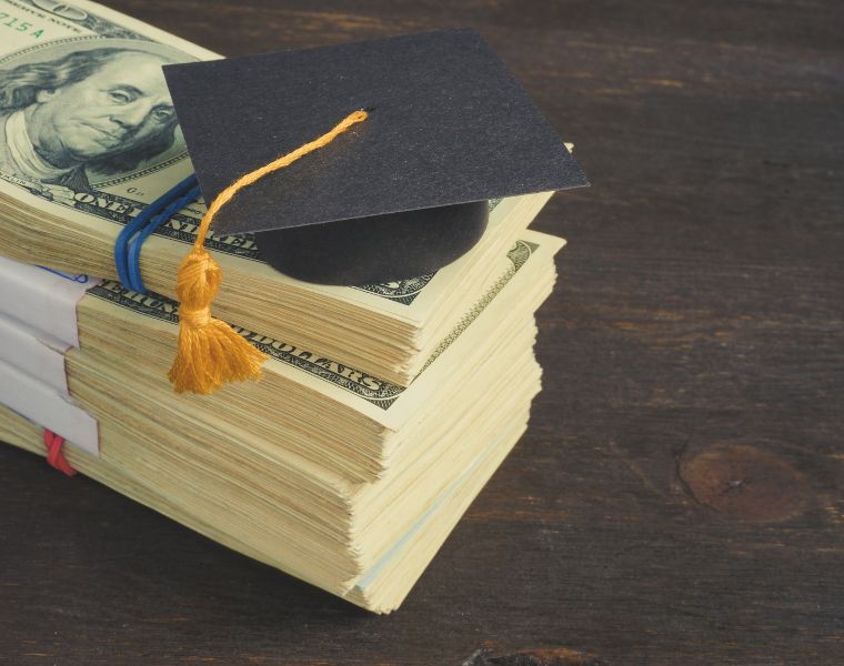 Savings for education and university concept. Stack of cash and graduation cap.
