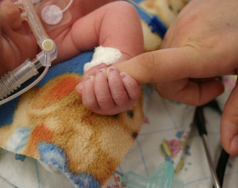 Image of a premature infant holding a finger in the nicu