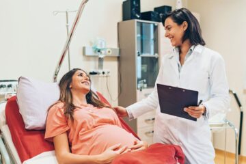 Pregnant woman lying down on a hospital bed and talking to a doctor