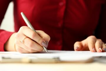Close up of woman holding a pen filling out a form