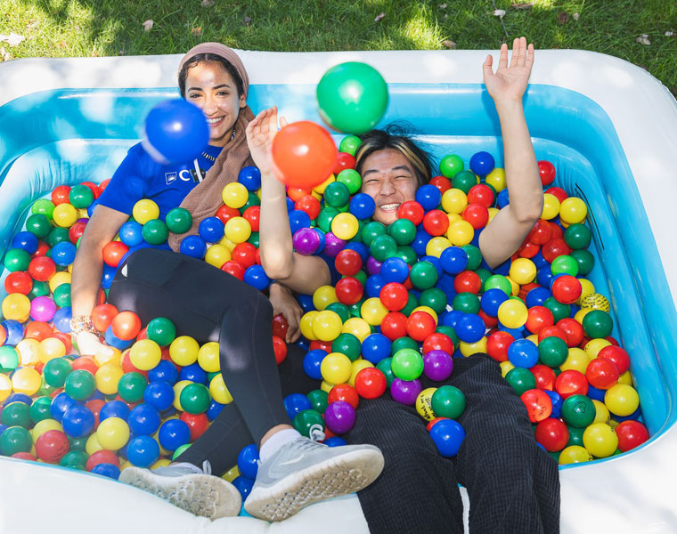 Two Case Western Reserve University students smile in an inflatable pool full of colorful balls