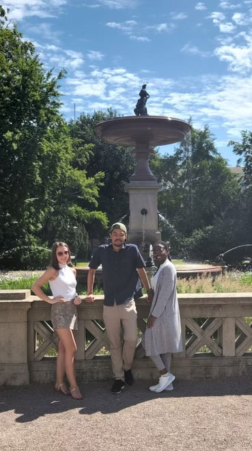 Photo of Darren Dorvil alongside two other students at a fountain in Sweden