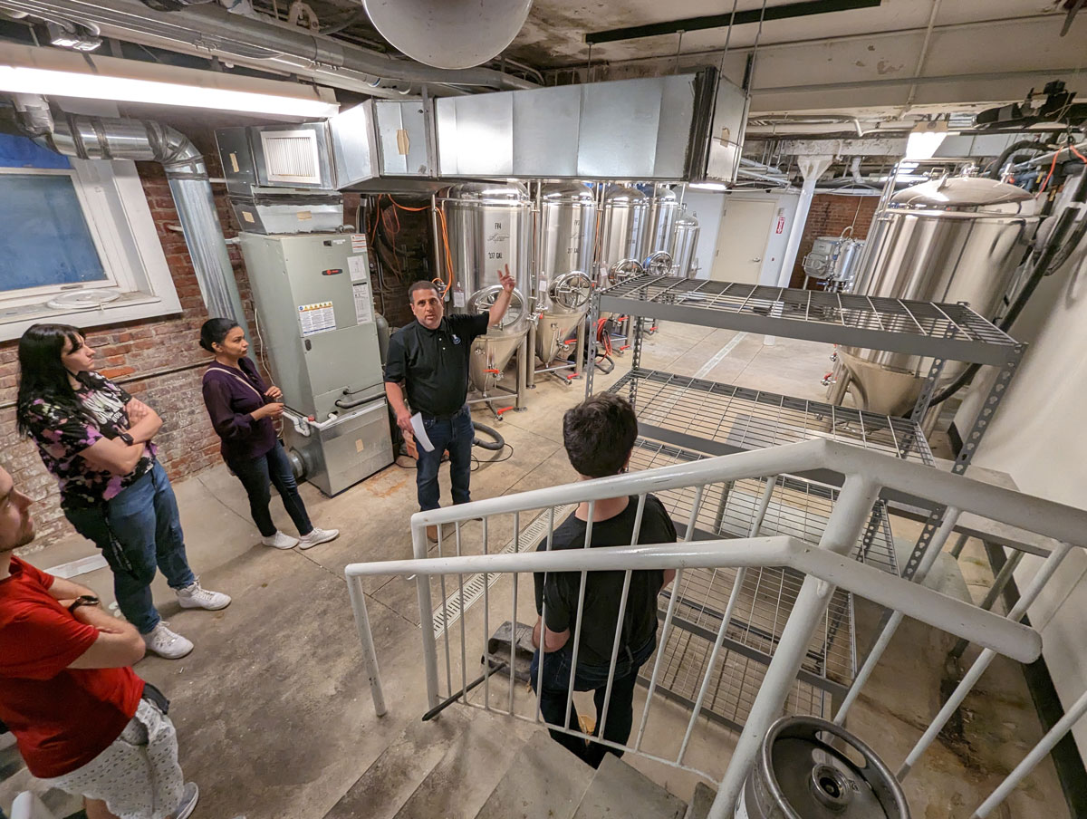 Photo of students in the Chemical and Biomolecular Engineering 430: Design and Production of Fermented Beverages course listening to a presentation by a guest speaker in a brewery