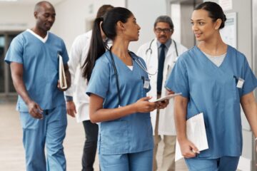 A diverse group of doctors and medical professionals walking and talking in a hospital setting.