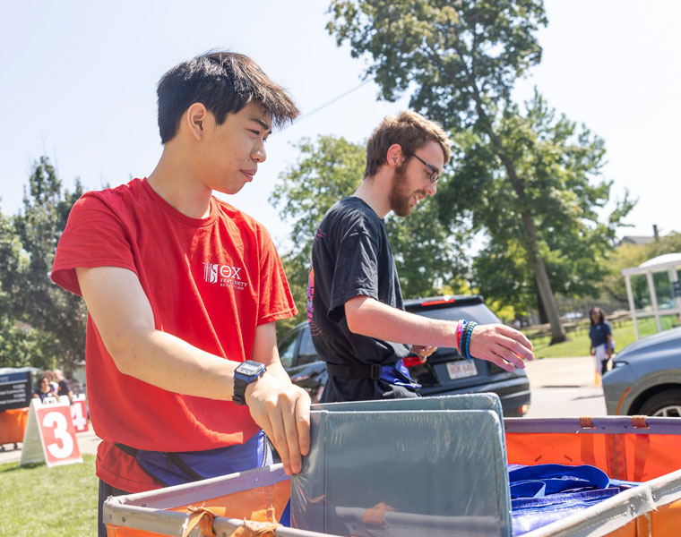 Case Western Reserve University student volunteers help load a bin at move-in