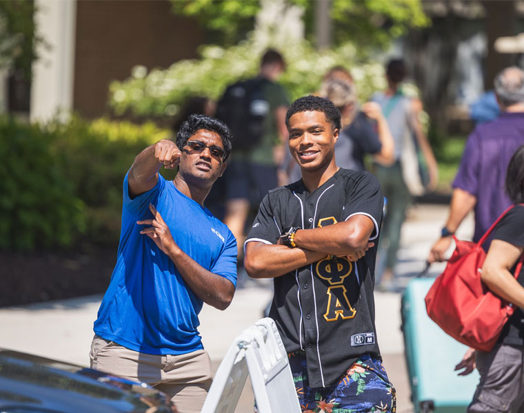 A Case Western Reserve University volunteer points out directions to a student during move-in