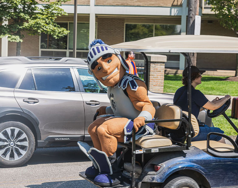 Case Western Reserve University mascot Spartie sits on the back of a golf cart during move-in
