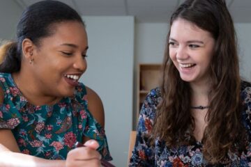 Two students in a dorm room laughing