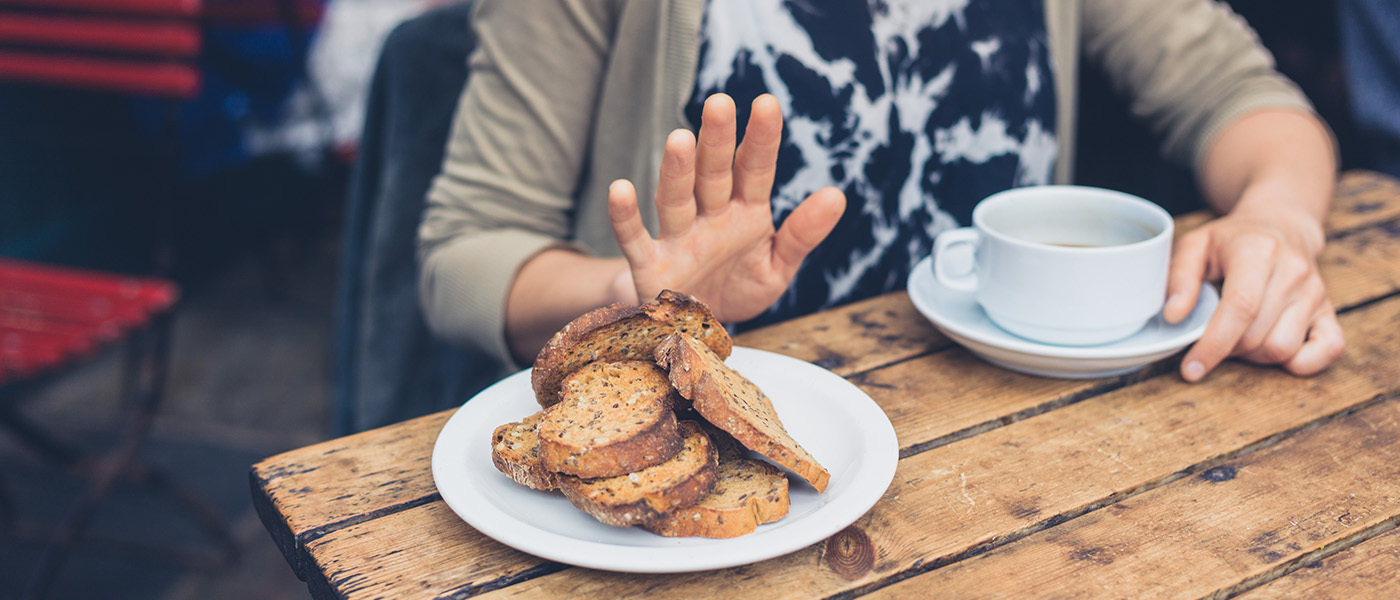 Photo of someone holding their hand up to a plate of bread on a table