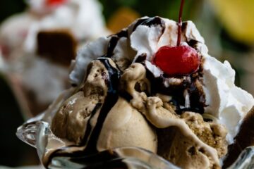 Chocolate ice cream sundae dessert topped with whipped cream, chocolate sauce and cherry
