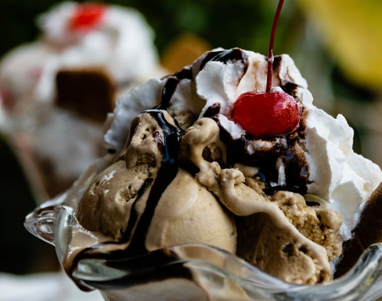 Chocolate ice cream sundae dessert topped with whipped cream, chocolate sauce and cherry