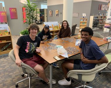 Happy students pose while making puzzles in the Zen Zone at Kelvin Smith Library. 