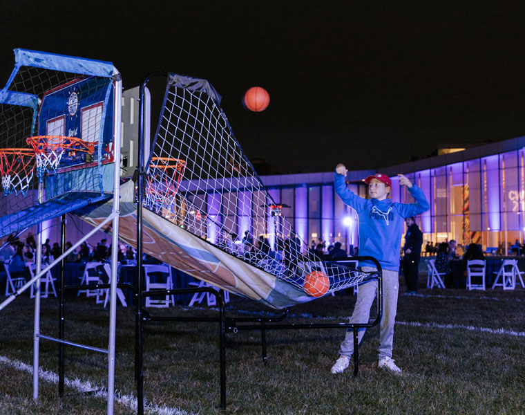 Photo of a student shooting a basketball for a game during Blue Bash